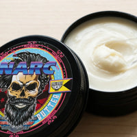 Macro view of the smooth, creamy texture of Flagship Soap Company’s NARC beard butter in an open 2 oz tin, highlighting the high-quality whipped consistency.