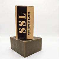 Side view of Flagship Soap Company "Cup of Joe" Mocha Coffee soap bar. The tan packaging prominently displays the mocha coffee scent and the circular "Shit-Shower-Lather" seal. This exfoliating coffee soap is a premium veteran-owned grooming product for men.