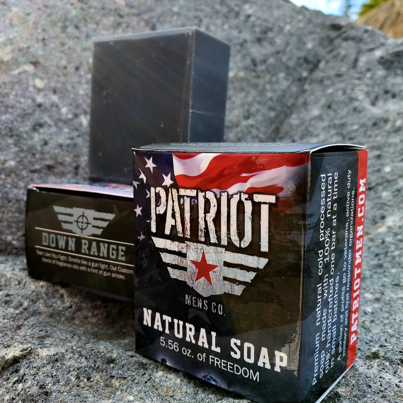 Down Range natural men's soap, smell's like gunpowder, by Patriot and Company activated charcoal soap with soap box against a rock.