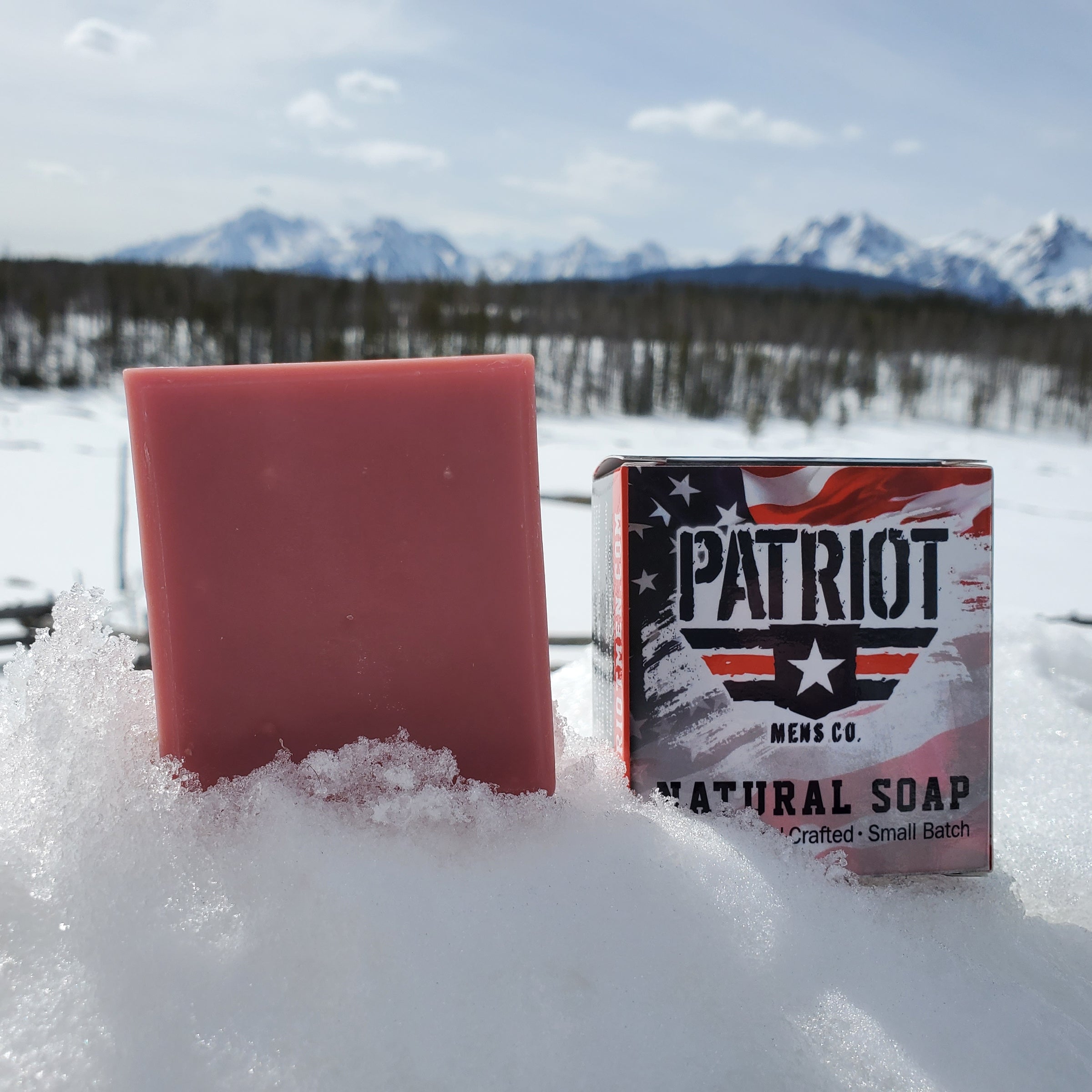 Unicorn men's natural soap with pink bar of soap and snow with Sawtooth Mountains in background.